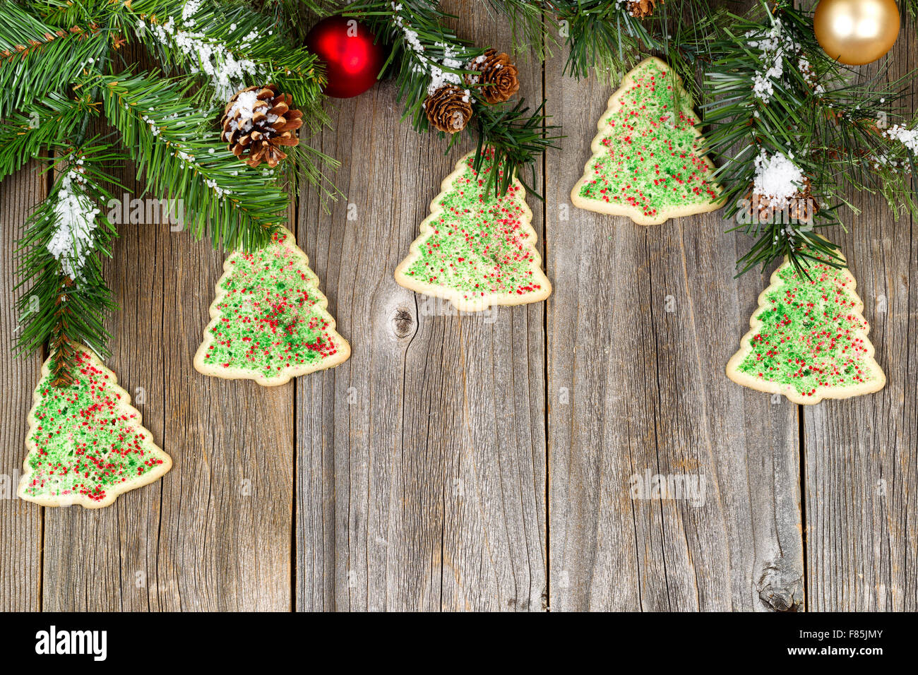 Angle de vue élevé en forme d'arbre avec des branches de conifères cookies, pommes de pin, de neige et ornements sur bois rustique. Banque D'Images