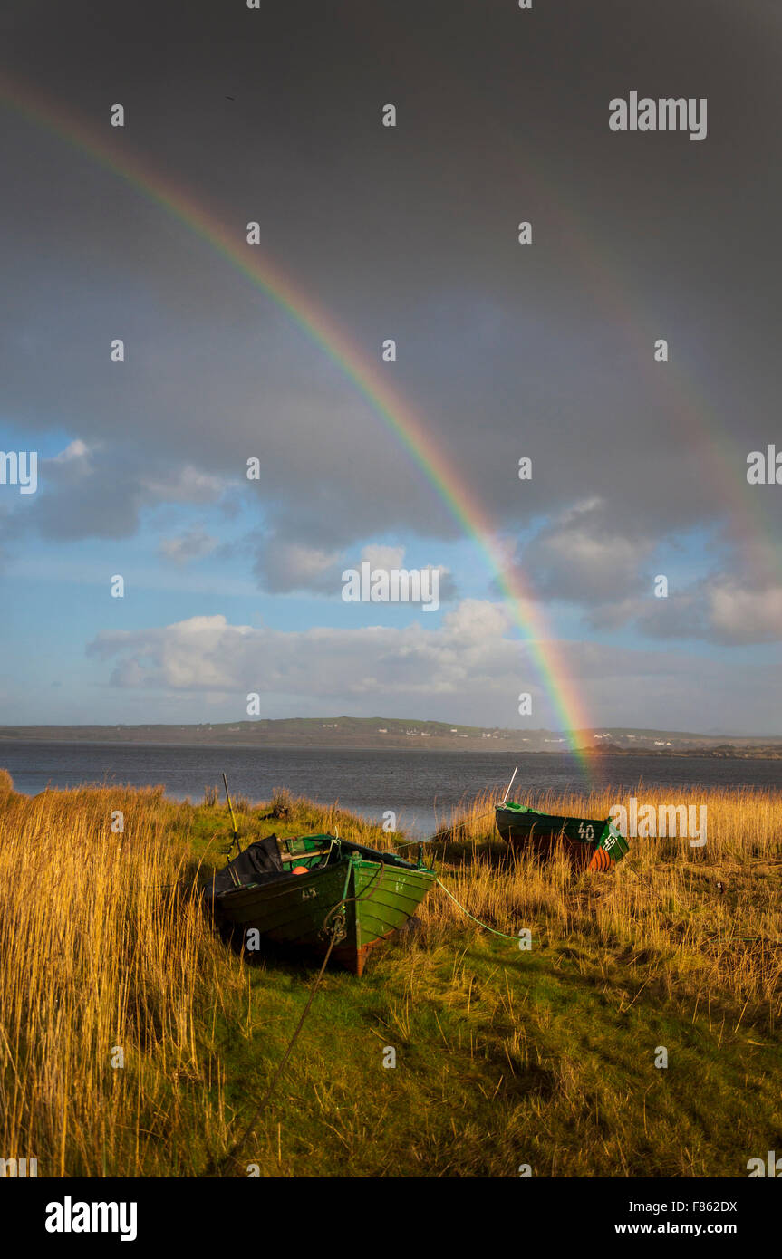 Ardara, comté de Donegal, Irlande la météo. 6e décembre 2015. Après deux jours de pluie incessante pendant une tempête Desmond un arc-en-ciel apparaît au-dessus des lits de roseaux et des bateaux de pêche sur la côte ouest. Crédit : Richard Wayman/Alamy Live News Banque D'Images