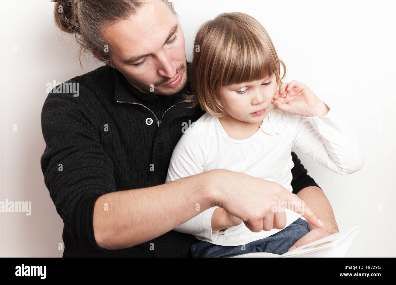 Young man reading book avec peu Caucasian girl, shoot studio Banque D'Images