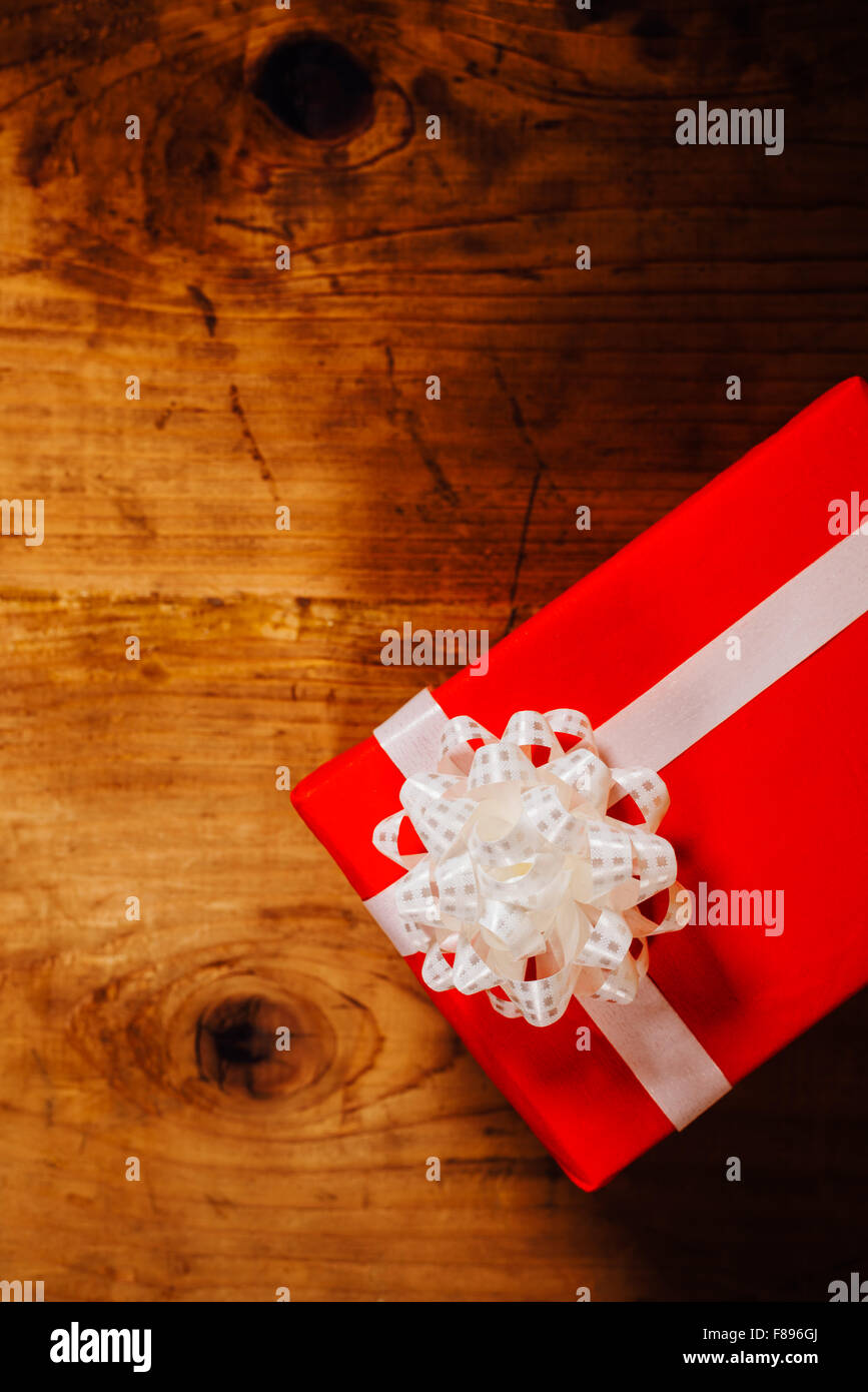 Boîte cadeau rouge avec ruban blanc sur la table en bois, vue du dessus Banque D'Images