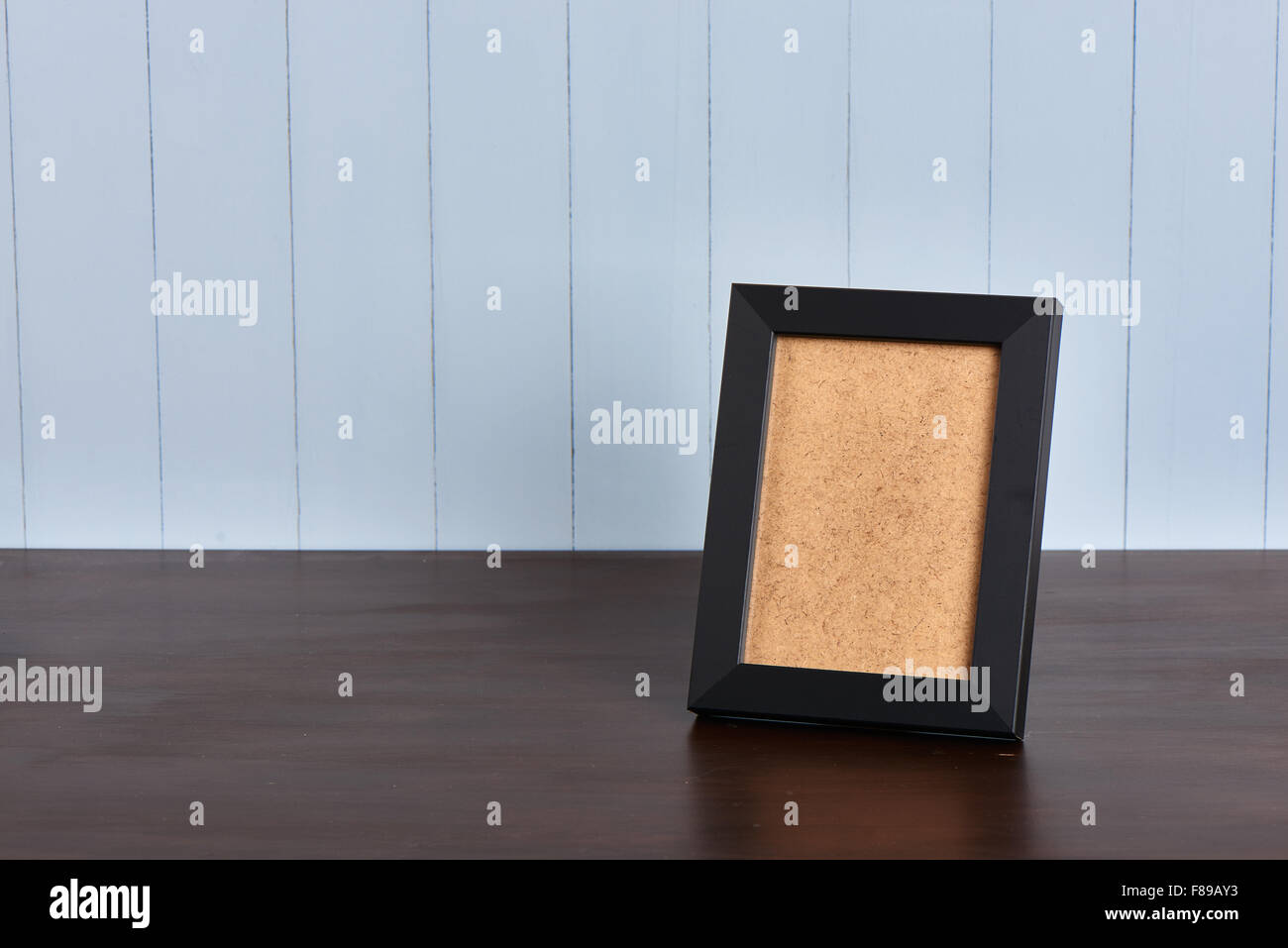 Cadre noir sur une table de bois sur un fond bleu fabriqué à partir de panneaux peints en bleu Banque D'Images