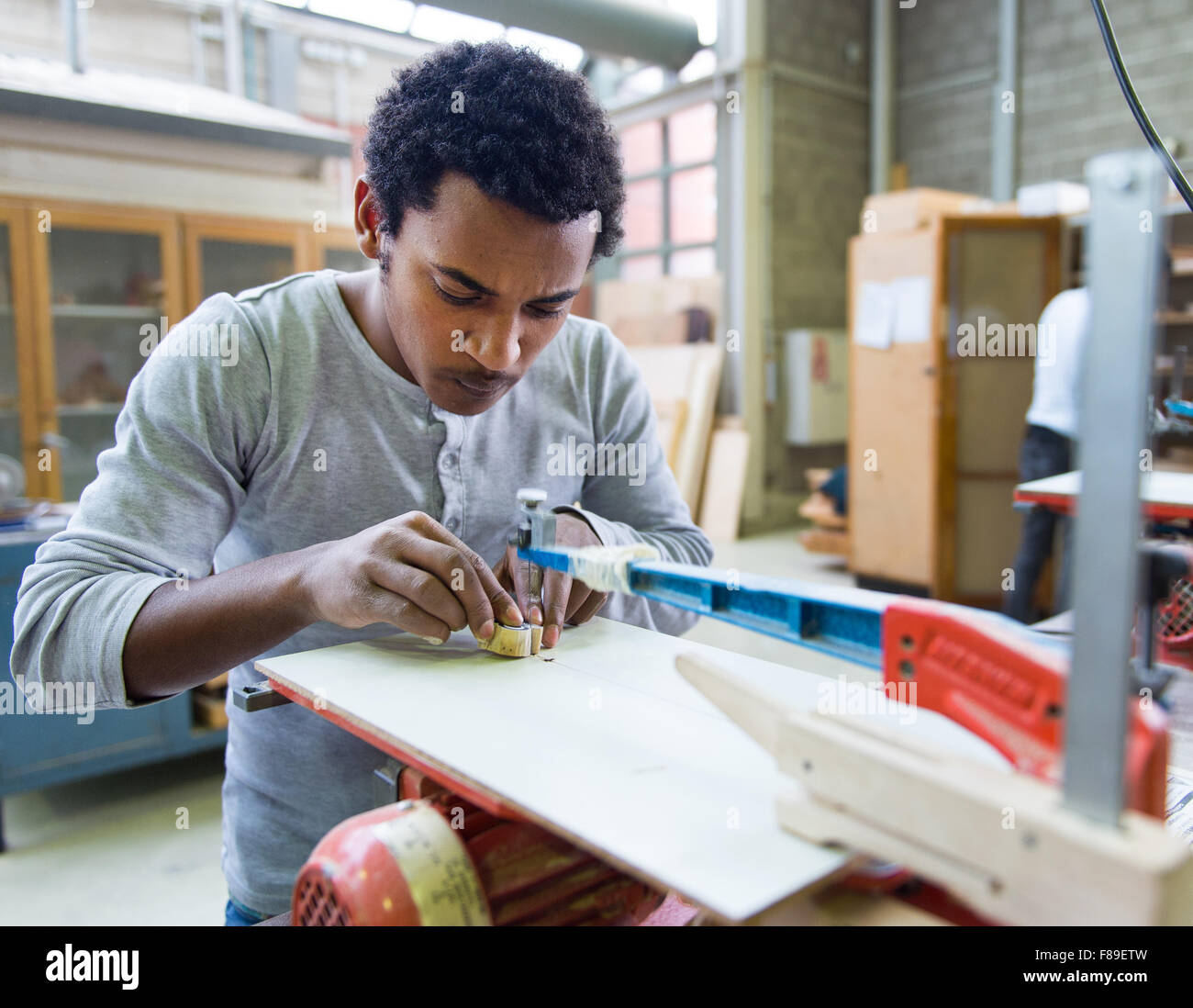 Le 17-year-old Mulue couper un morceau de bois pendant un cours d'un atelier de coupe de bois à Recklinghausen, Allemagne, 07 décembre 2015. Dans le monde 2014 college Mitte von TÜV NORD College, une 'classe' de l'éducation internationale a été mis en place dans lequel 29 recevoir des demandeurs d'asile, les compétences, langues et métiers afin de les former et d'augmenter leurs chances de trouver un emploi. Photo : MONIKA SKOLIMOWSKA/dpa Banque D'Images