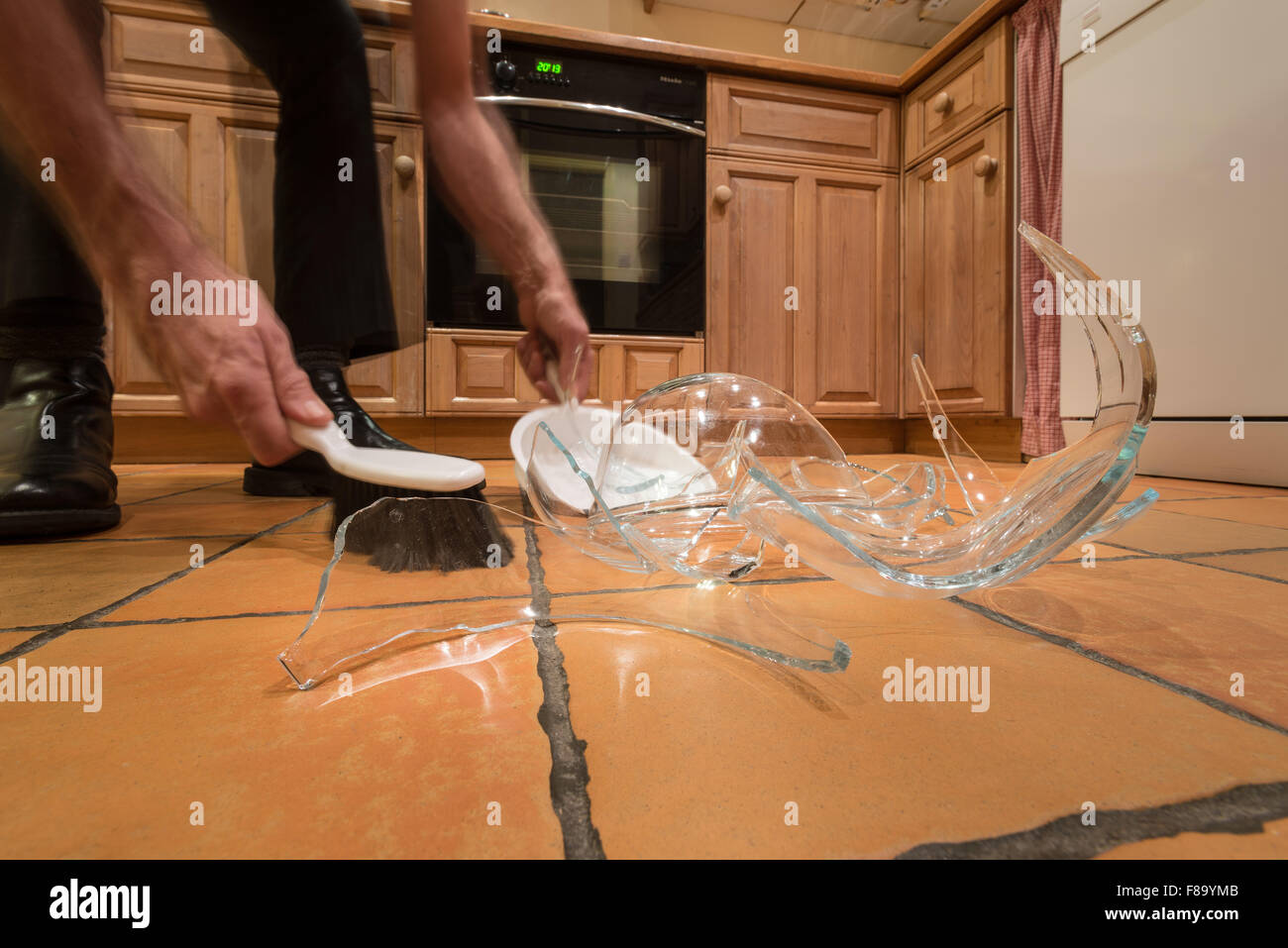 Pile de débris de verre brisé sur le plancher après l'accident et bol en verre pyrex sortit de mains humides renversé posé sur marbre Banque D'Images