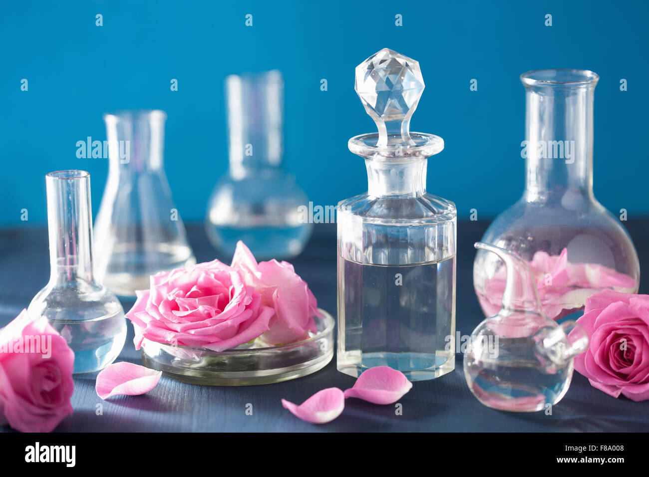 L'alchimie et l'aromathérapie avec des fleurs roses et des flacons de produits chimiques Banque D'Images