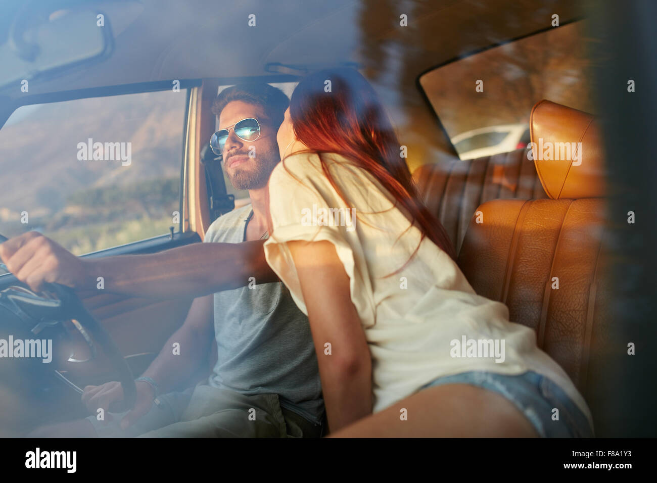 Woman kissing man driving car. Couple on road trip. Couple romantique en vacances s'amuser en voiture. Banque D'Images
