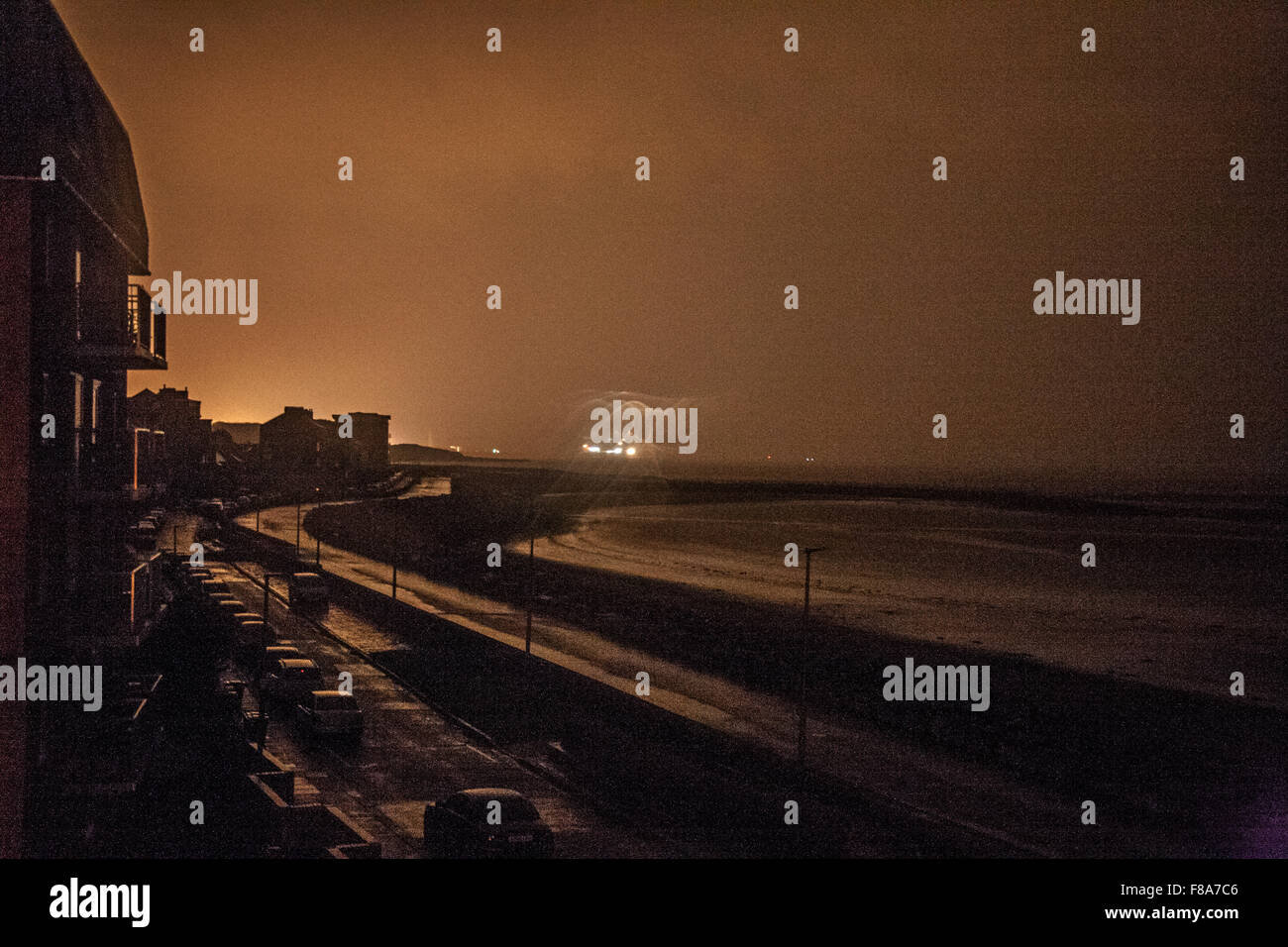 Sandylands Heysham, Promenade, Morecambe Royaume-uni 8 Décembre 2015 Une Eirie vue tenir avec une lumière pour ne pas être vu sur Sandylands Promenade à Morecambe illustré sous la lumière réfléchie sur les nuages de la centrale nucléaire d'Heysham et les lumières sur un ferry au départ du Terminal de Ferry de Heysham. La poursuite de coupures de courant que connaît l'ensemble de Morecambe et Lancaster au lendemain de l'inondation endommagée qui effectue le Lancaster Poste le dimanche. Crédit : David Billinge/Alamy Live News Banque D'Images