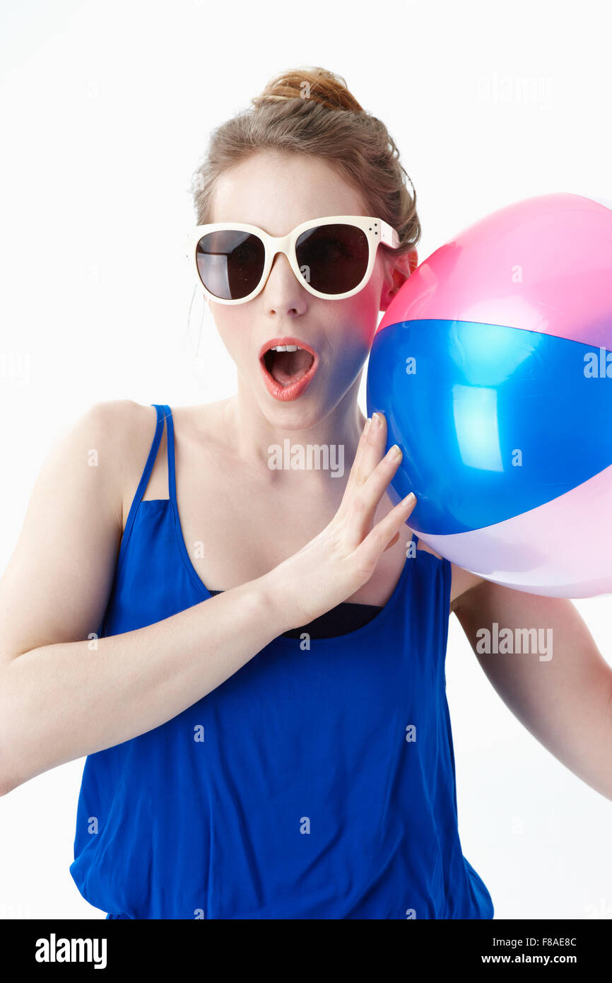 Surpris femme avec un ballon de plage portant des lunettes de soleil Banque D'Images