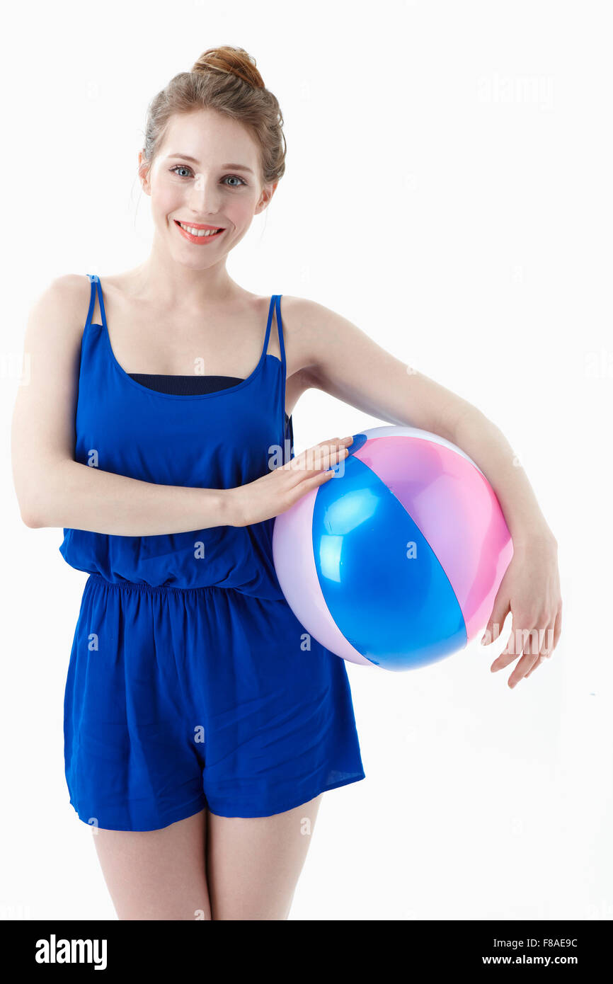 Femme en robe bleue tenant un ballon de plage sous le bras Banque D'Images