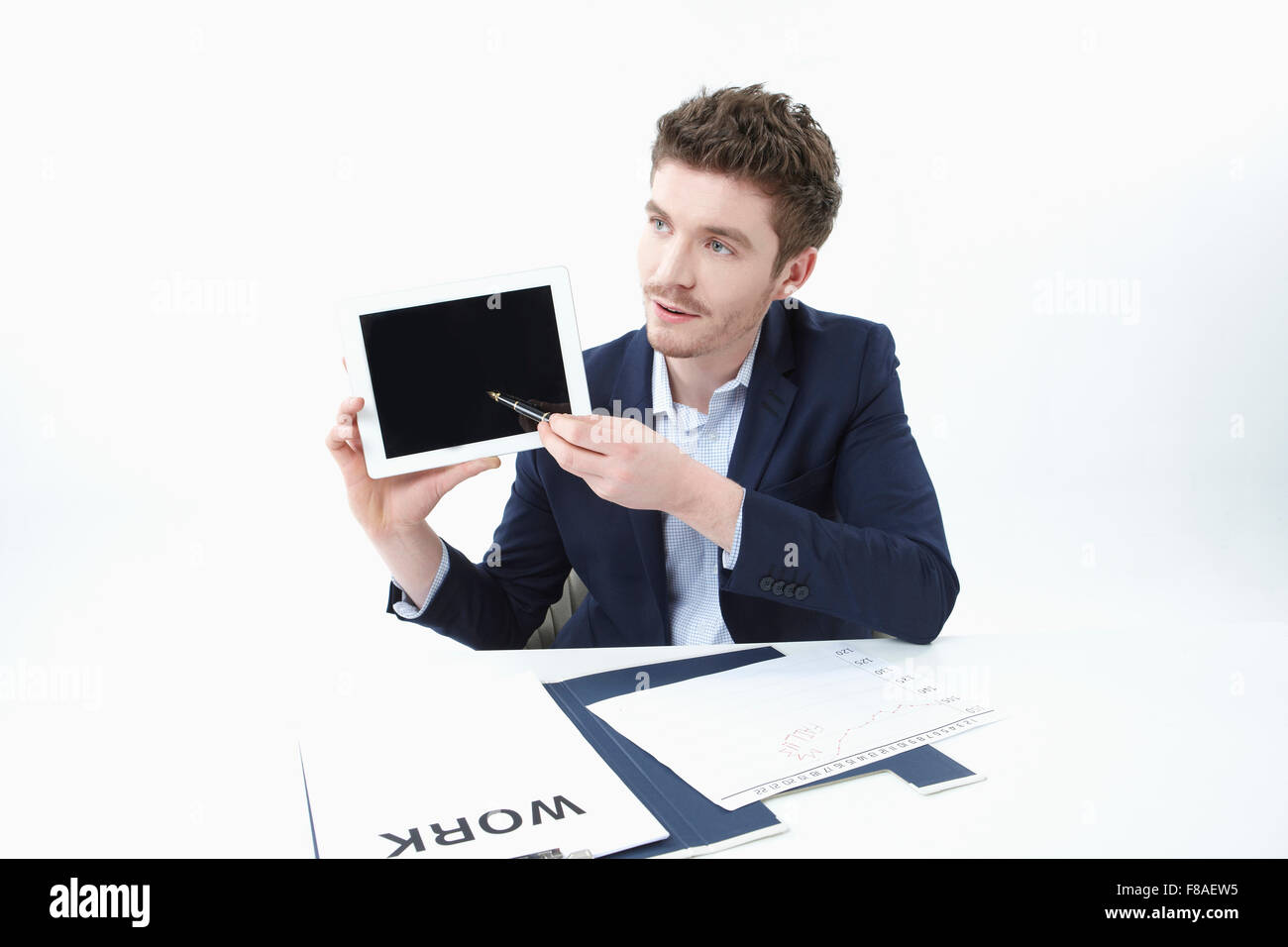 Businessman holding tablet PC et le pointant avec un stylo Banque D'Images