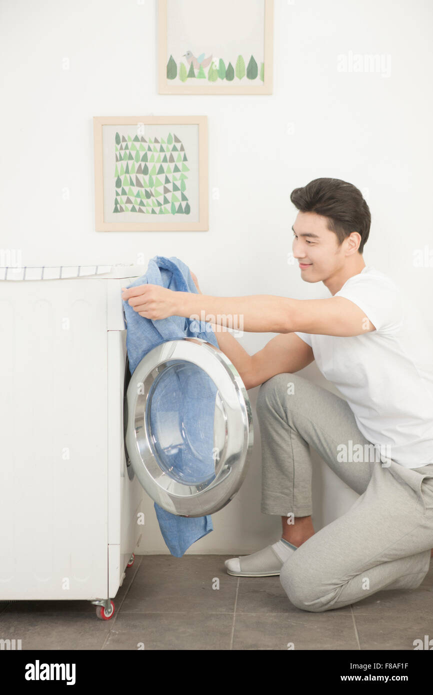 Homme tenant une chemise en avant de l'ouvrir une laverie automatique Banque D'Images