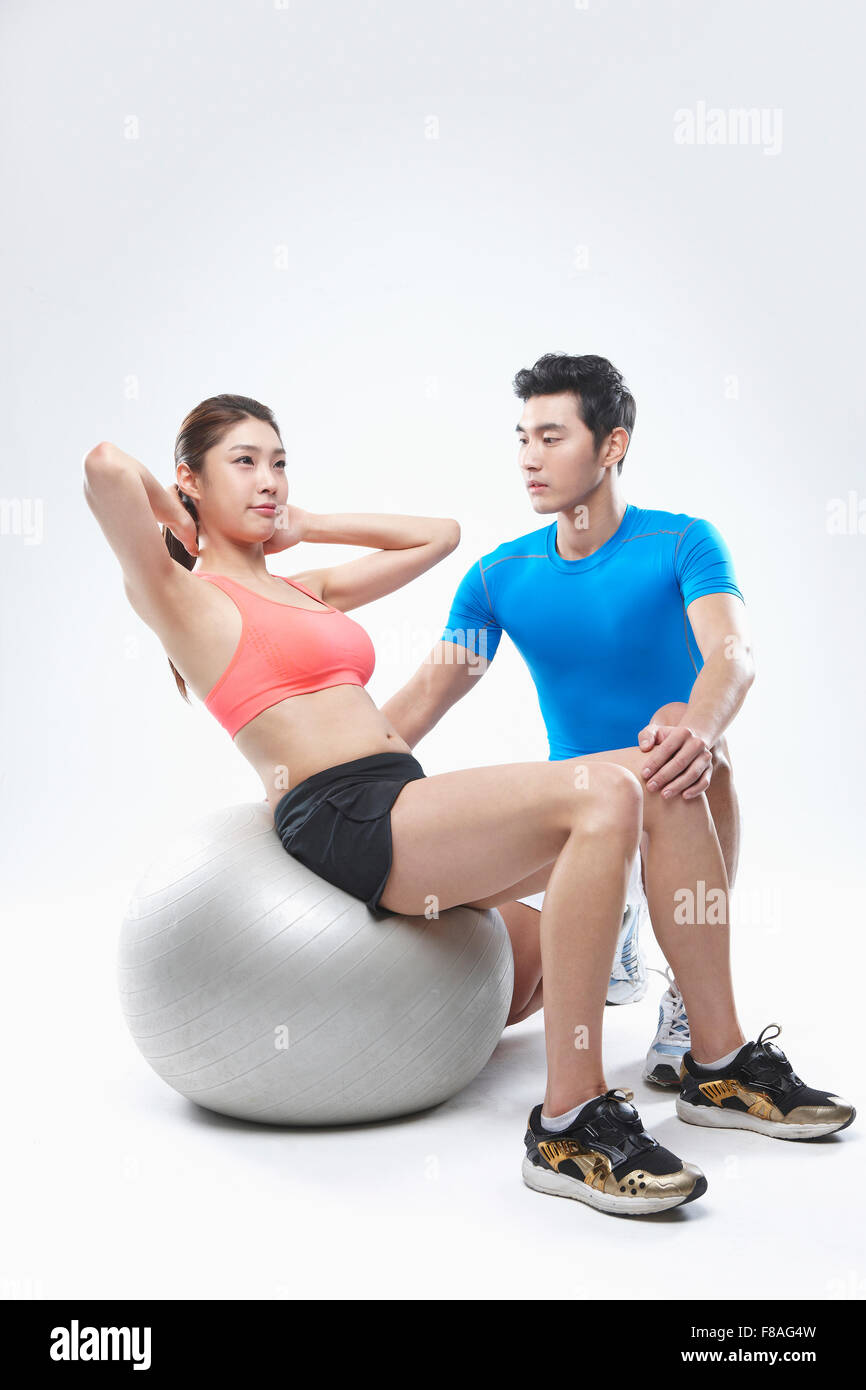 Woman doing sit-ups sur ballon de gymnastique et l'entraînement de l'homme à côté d'elle Banque D'Images