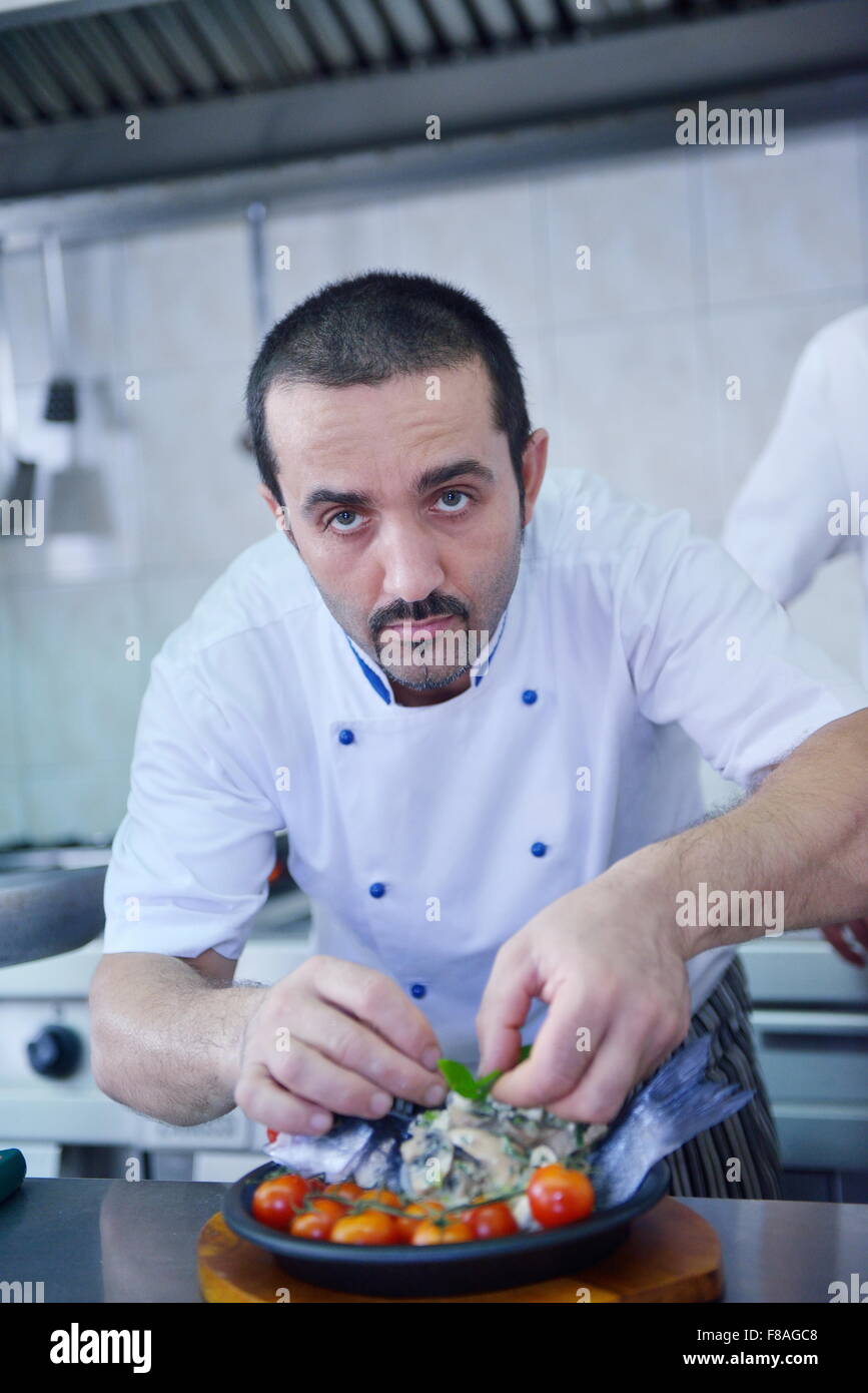 Beau chef habillé en blanc décoration uniforme de la salade de pâtes et de fruits de mer le poisson dans une cuisine moderne Banque D'Images