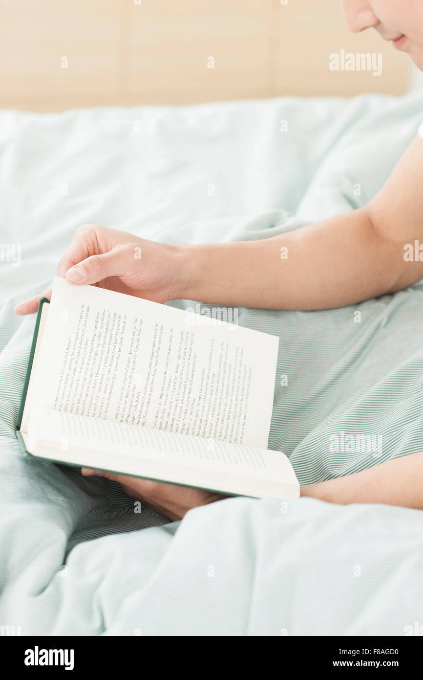 Livre lu par un homme au lit Banque D'Images