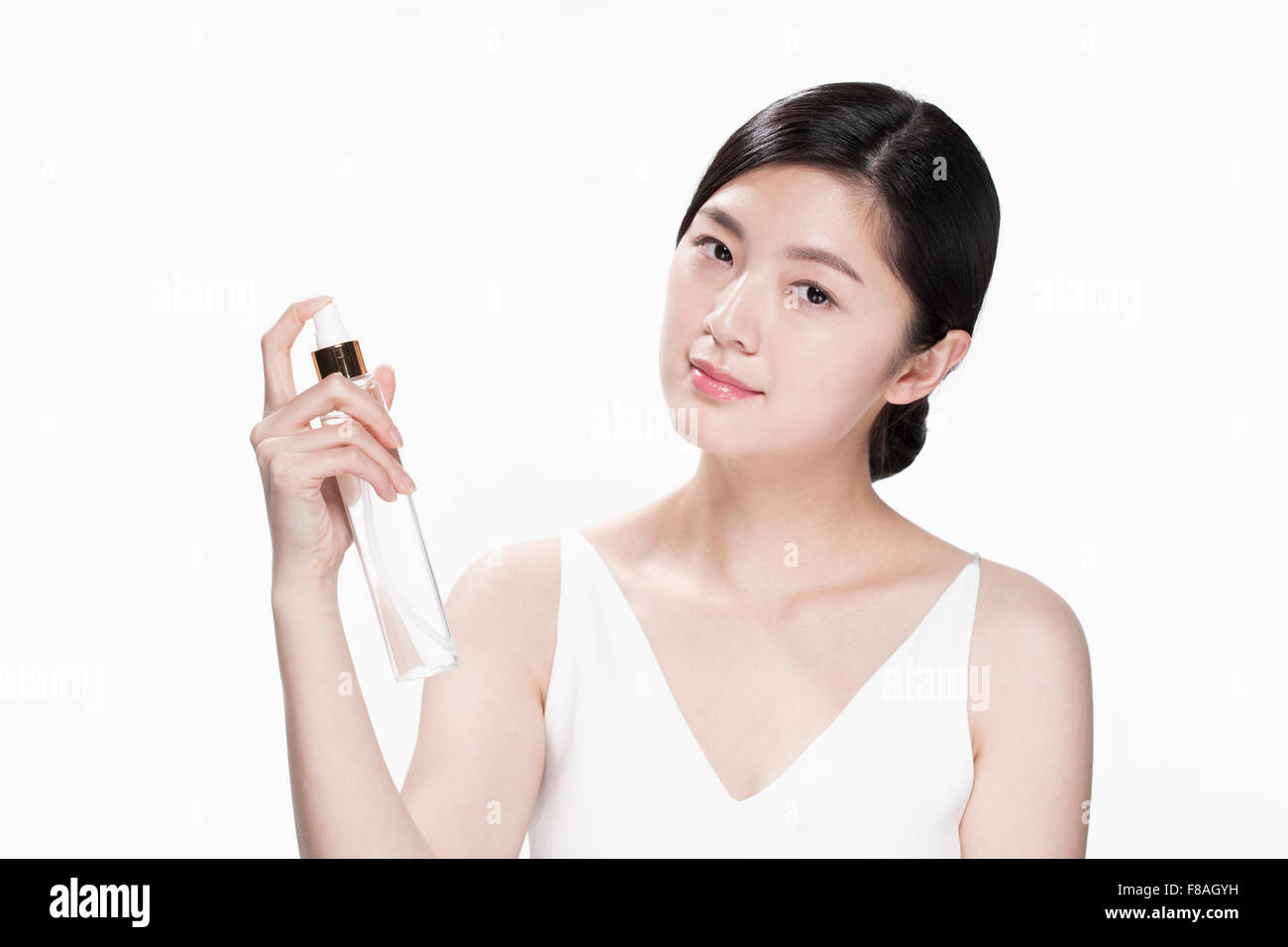 Young Asian woman holding a brume faciale visant à son visage et l'avant Banque D'Images