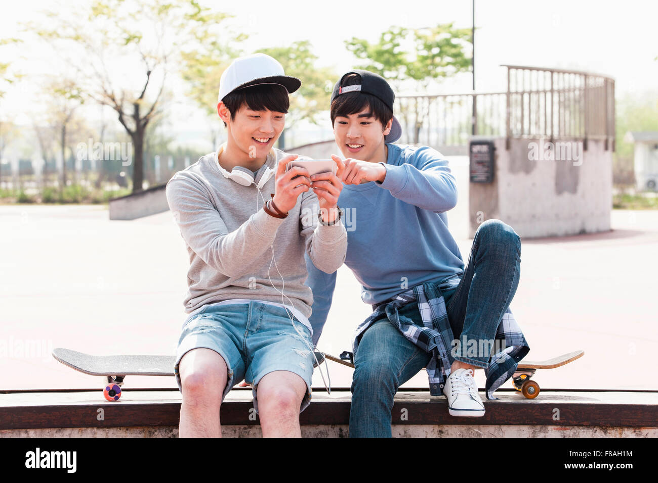 Deux hommes assis sur des planches de skate et à un ensemble de téléphone Banque D'Images