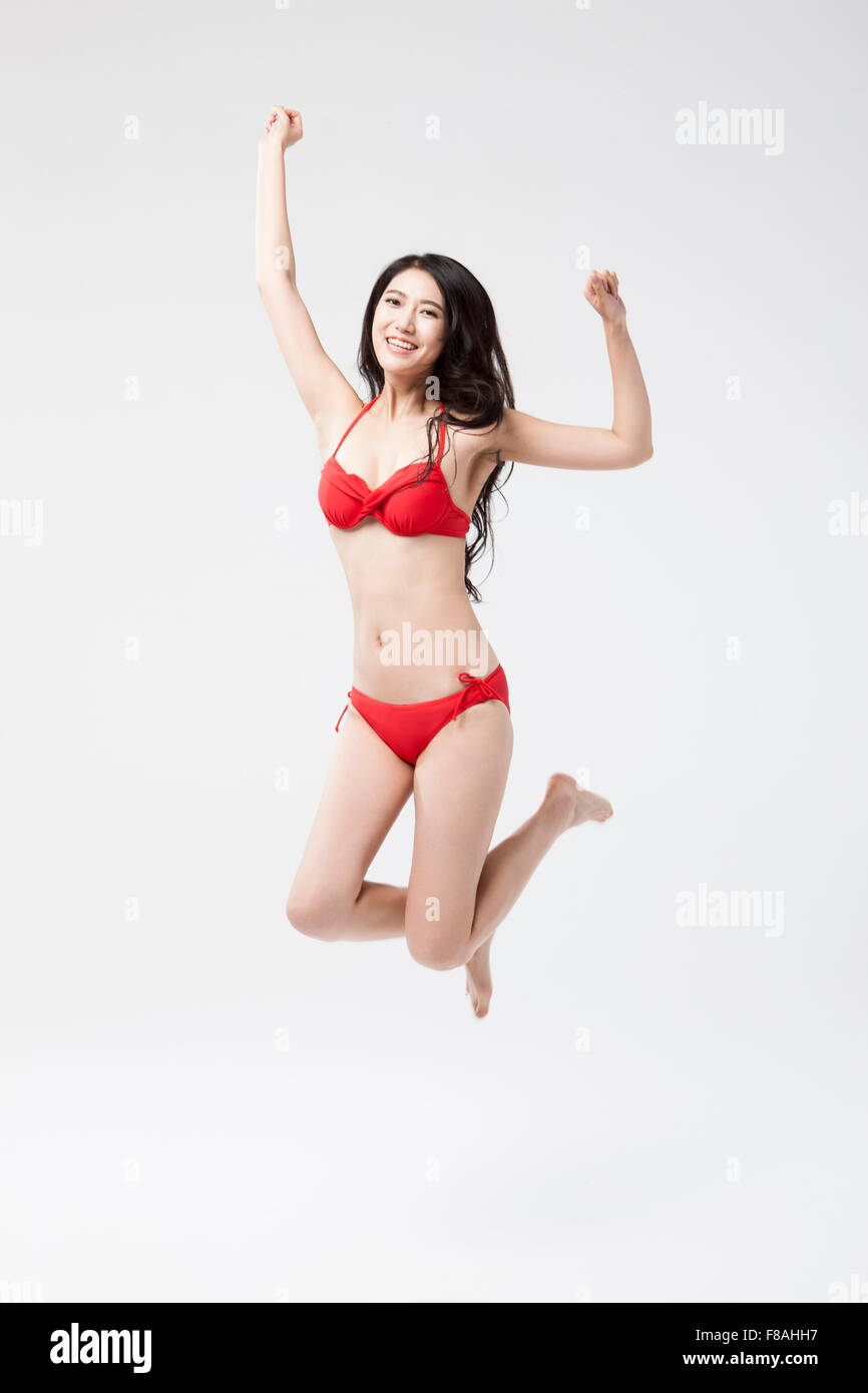 Asian Woman in bikini jumping usure avec ses mains en hauteur Banque D'Images