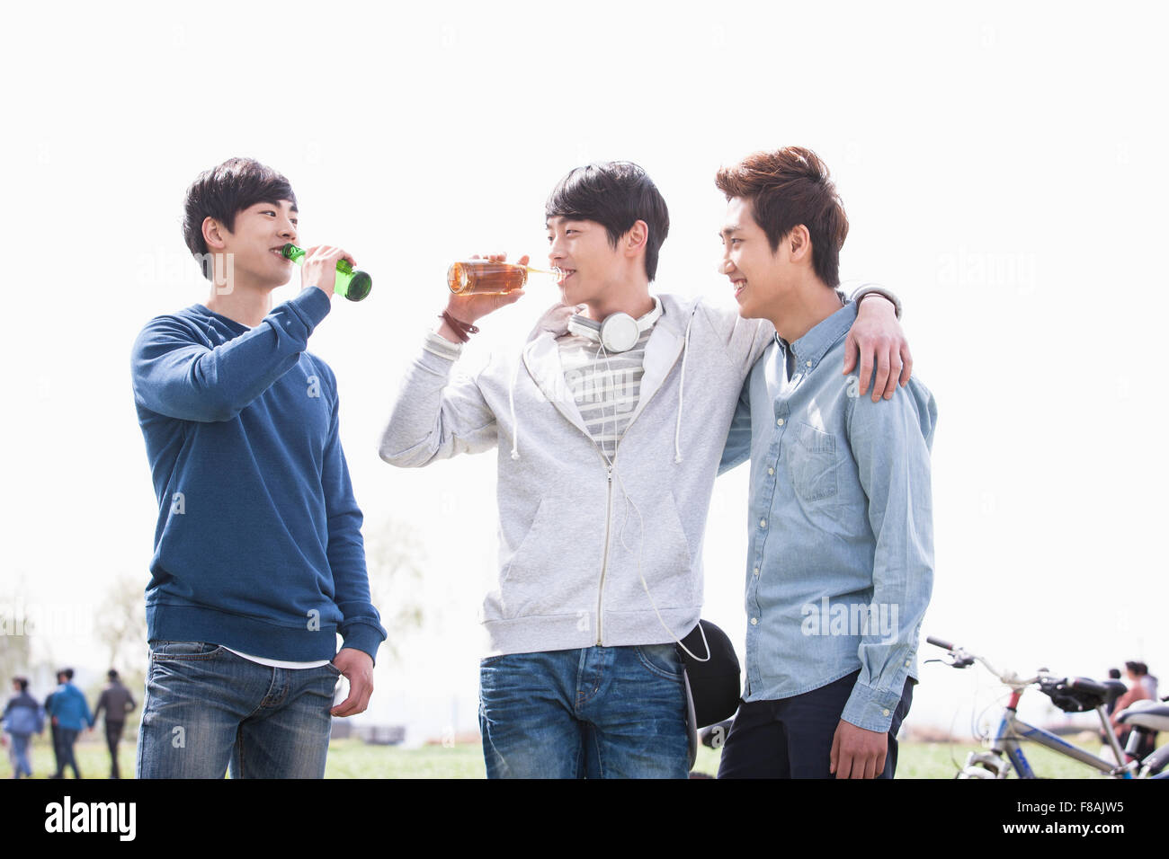 Trois jeunes hommes s'amuser au parc avec des bières Banque D'Images