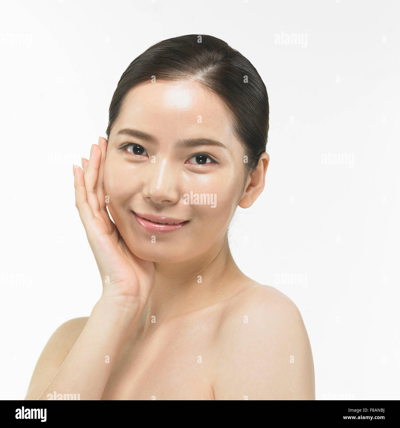 Portrait of smiling Korean woman staring at/touching her face Banque D'Images