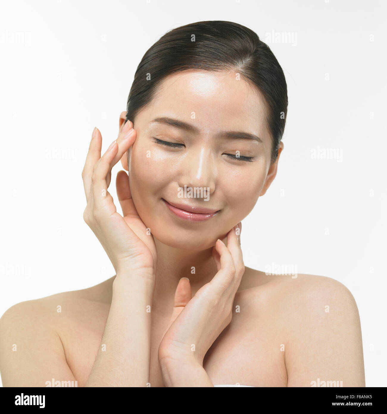 Portrait of smiling Korean woman touching her face fermer les yeux avec les doigts Banque D'Images