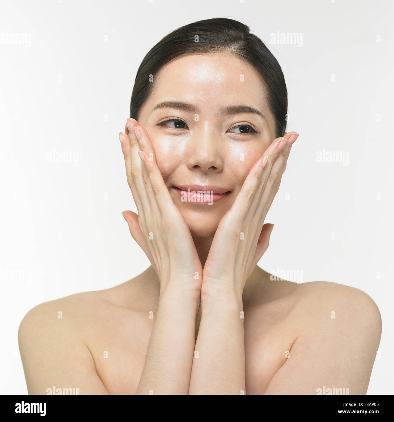 Portrait de femme coréenne envelopper son visage avec les mains à la recherche vers le bas avec un sourire Banque D'Images