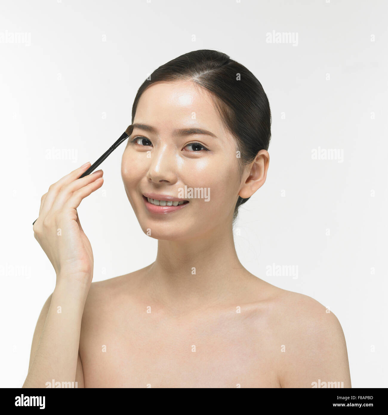 Portrait de femme coréenne dessin sourcil avec une brosse à regarder devant avec un sourire Banque D'Images