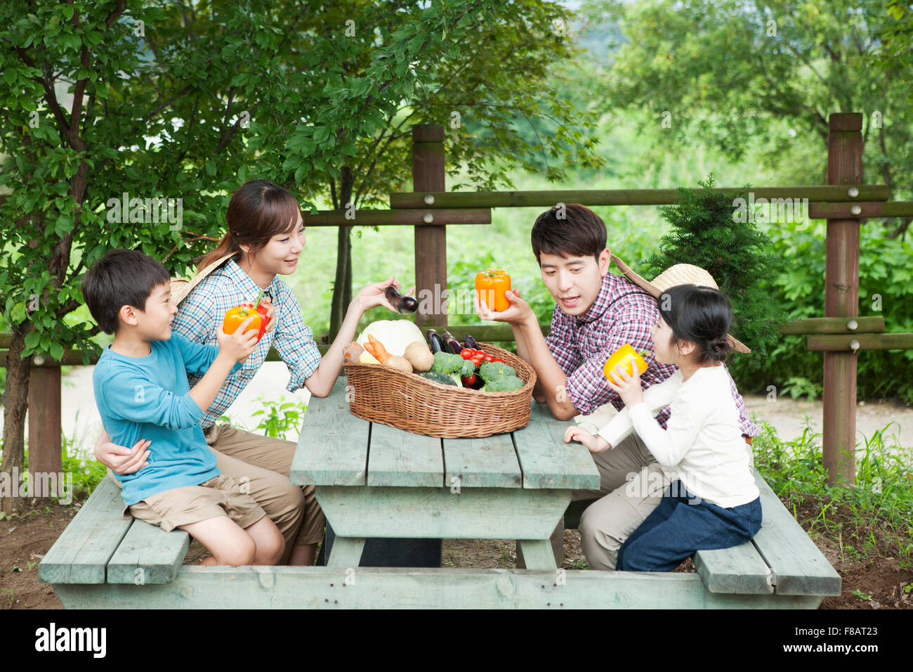 Famille assis autour d'une table avec des légumes frais à l'air libre Banque D'Images