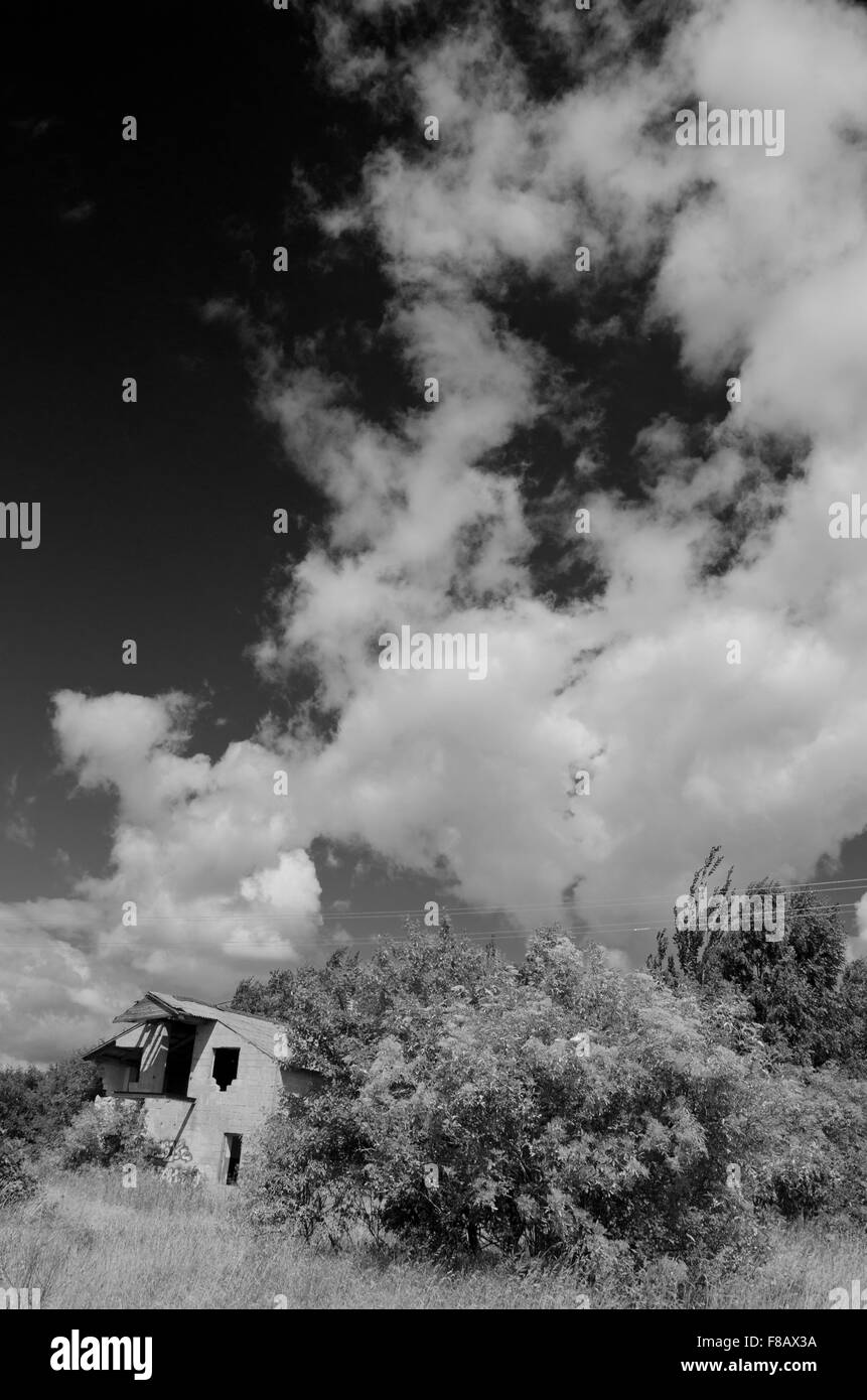 Paysage rural avec des nuages et maison abandonnée, noir et blanc Banque D'Images