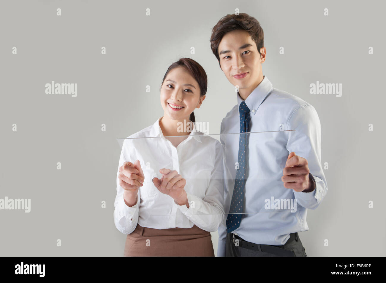 L'homme et la femme dans des tenues officielles tenant ensemble de l'écran tactile et souriant de l'avant Banque D'Images