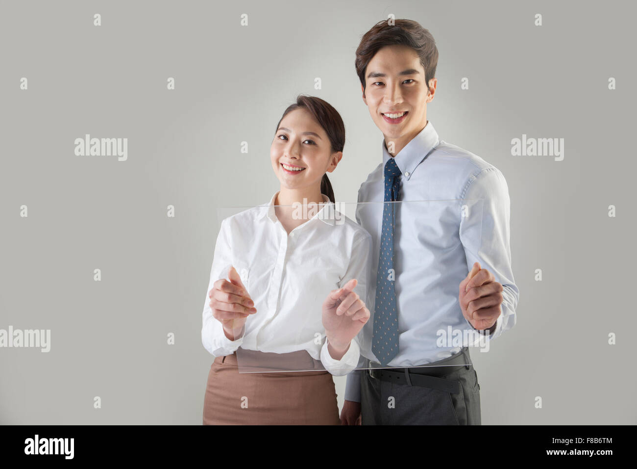 L'homme et la femme dans des tenues officielles holding les écrans tactiles et regardant vers l'avant avec un sourire Banque D'Images