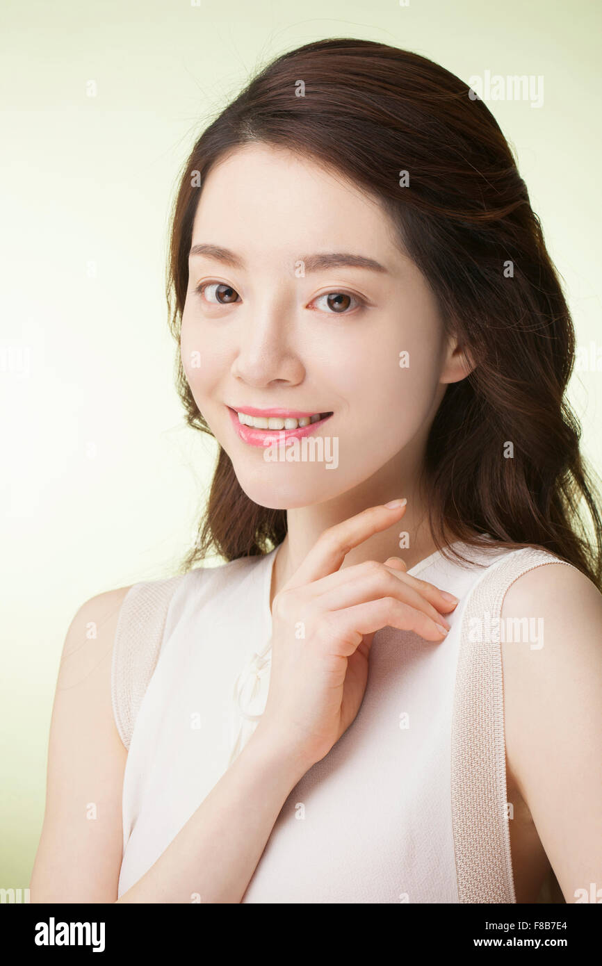 Femme coréenne avec la longue chevelure ondulée en t-shirt blanc de l'avant et regarder smiling Banque D'Images