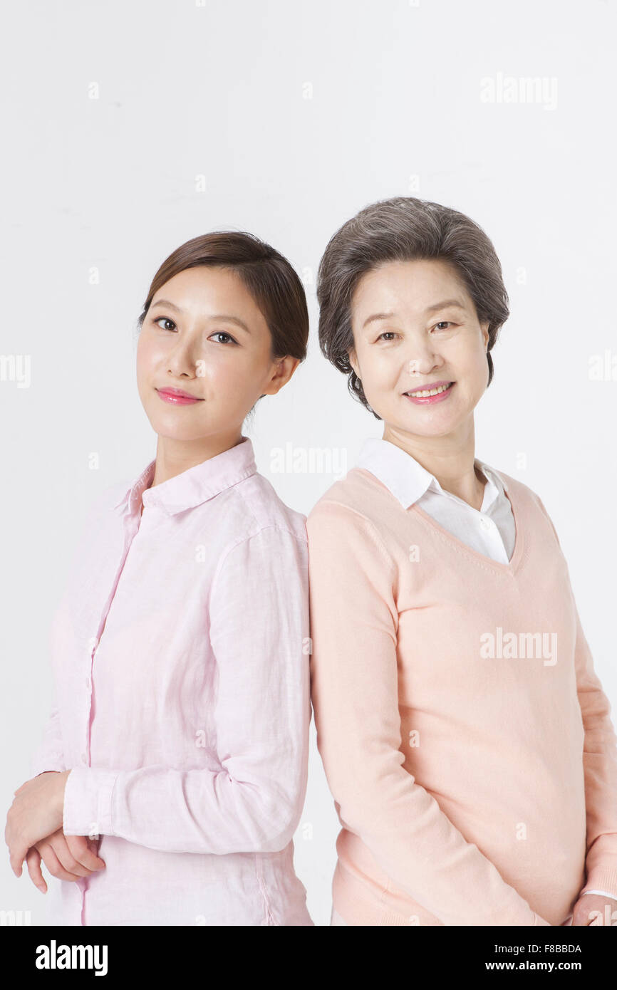 Mère et fille grandi debout dos à dos les uns les autres et de l'avant avec un sourire Banque D'Images