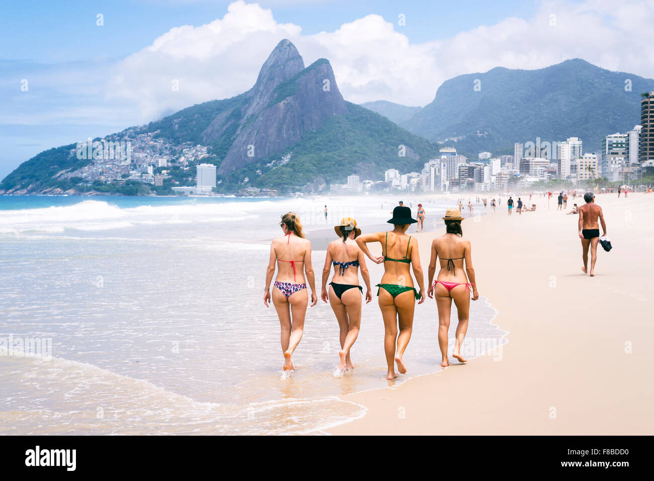 RIO DE JANEIRO, Brésil - 24 octobre 2015 : un groupe de jeunes femmes en costume de bain promenade le long du rivage de la plage d'Ipanema. Banque D'Images