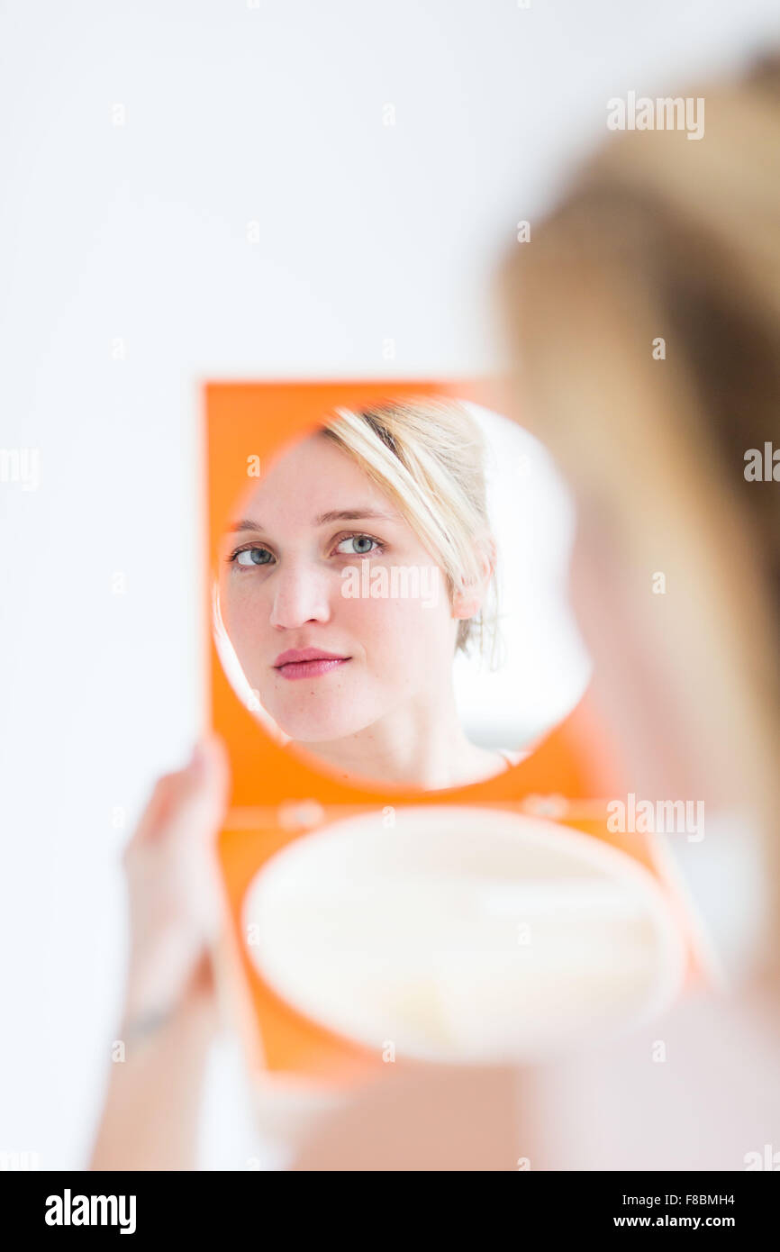 Femme contrôler son visage dans le miroir. Banque D'Images