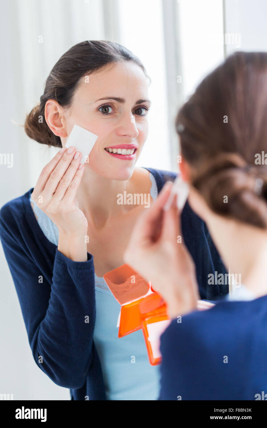 Femme à l'aide de papier buvard contre la peau qui brille . Banque D'Images