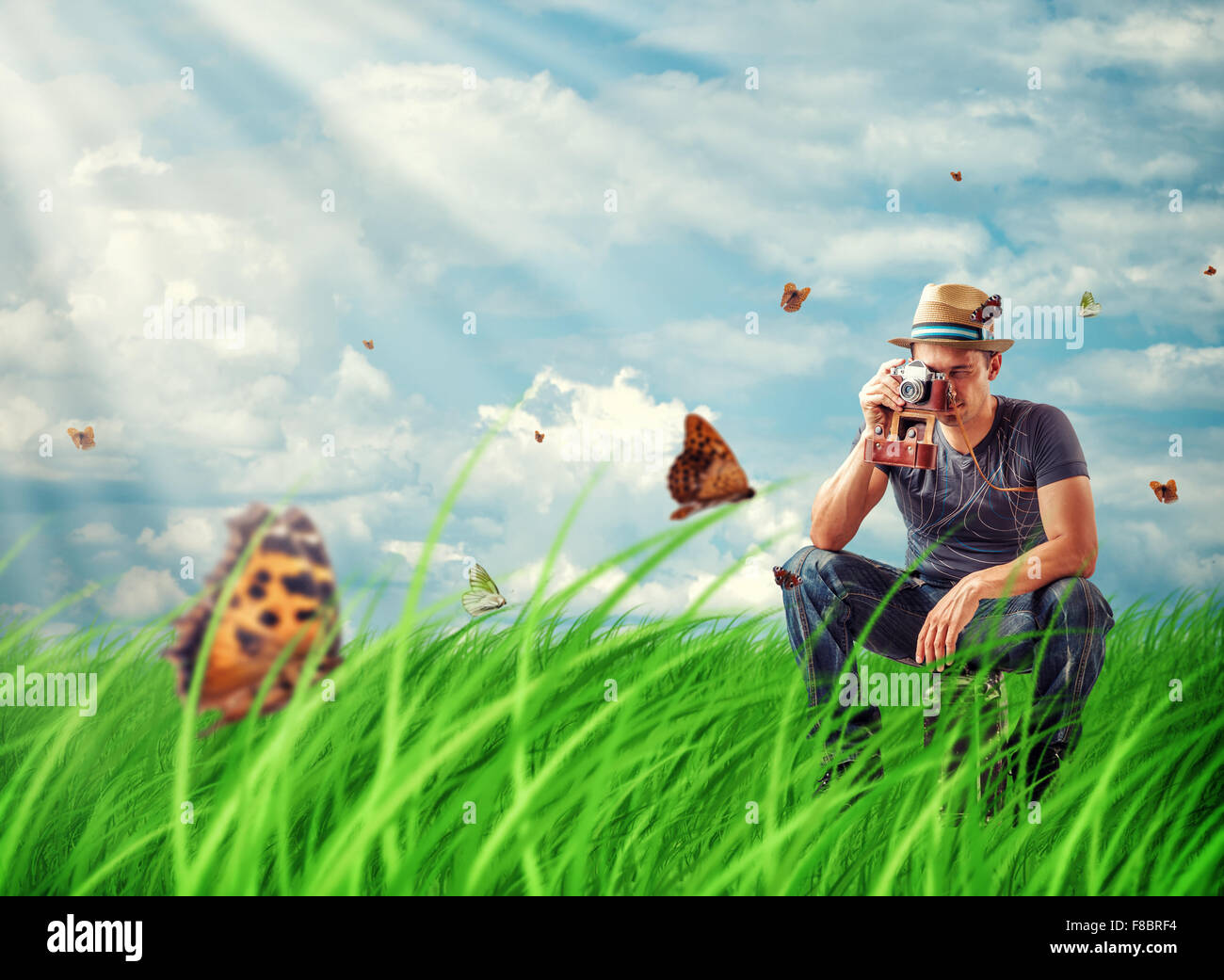 Jeune homme traveller photographier les papillons sur film retro caméra dans la prairie Banque D'Images
