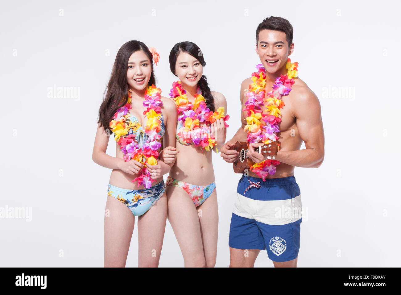 Deux femmes en bikini et un homme en portant des colliers de fleurs pantalon natation Banque D'Images