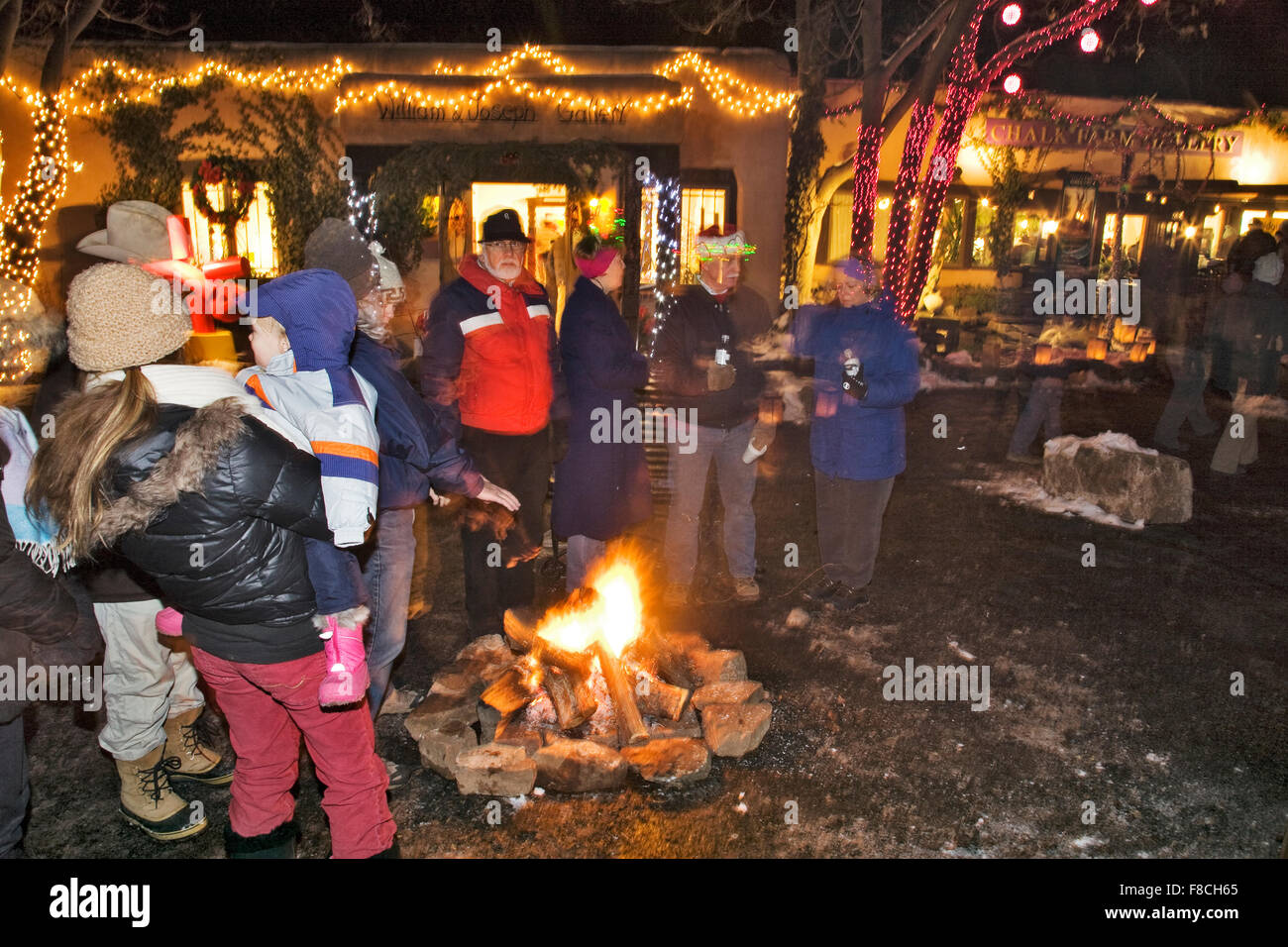 Les poussettes se réunir autour d'un petit feu de camp ou luminaria pour se réchauffer pendant la fête de Noël annuelle. Banque D'Images