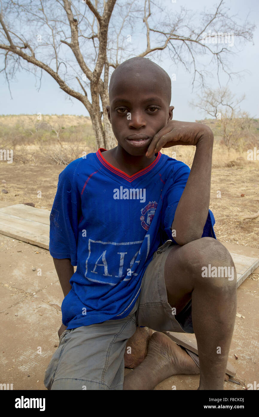 Jeune garçon à la recherche de l'Afrique à l'appareil photo avec un paysage aride Banque D'Images