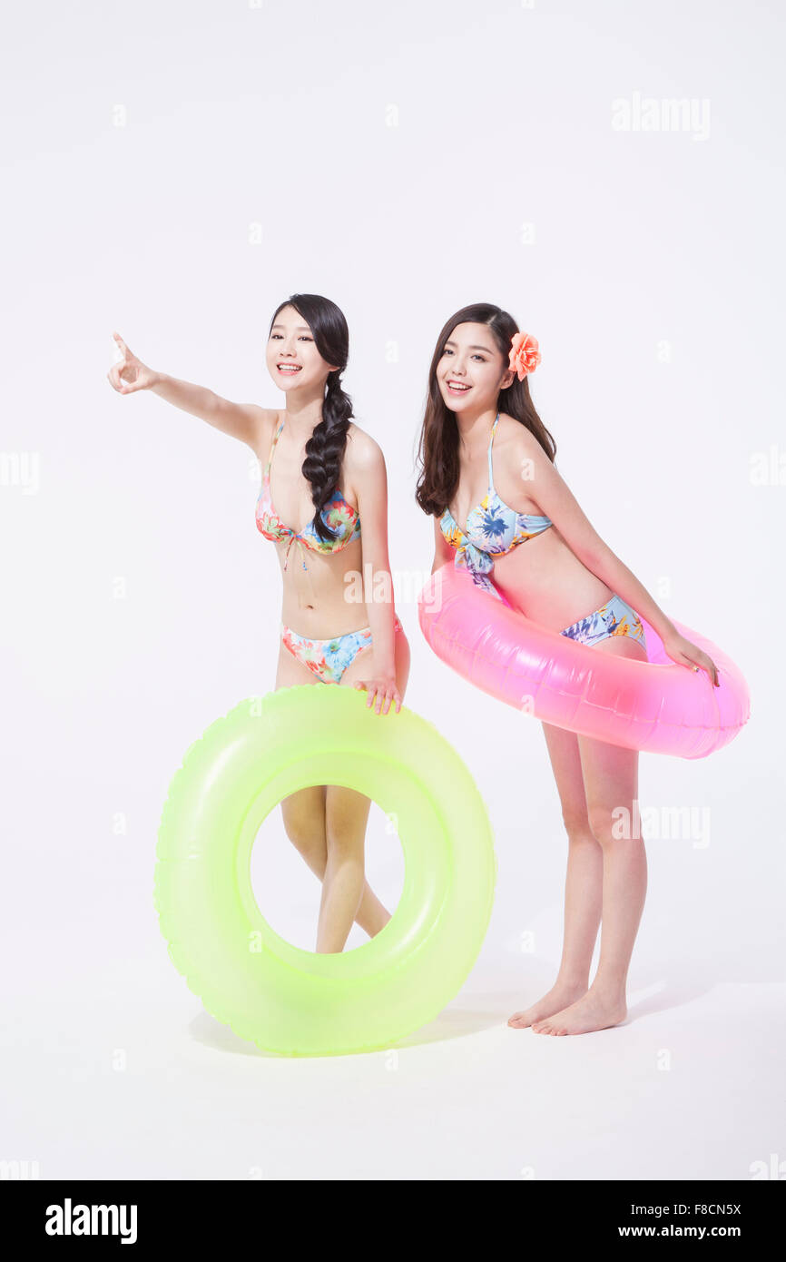 Deux femmes en bikini tenant un tube de l'anneau et chaque comité permanent et une femme pointant avec son doigt Banque D'Images