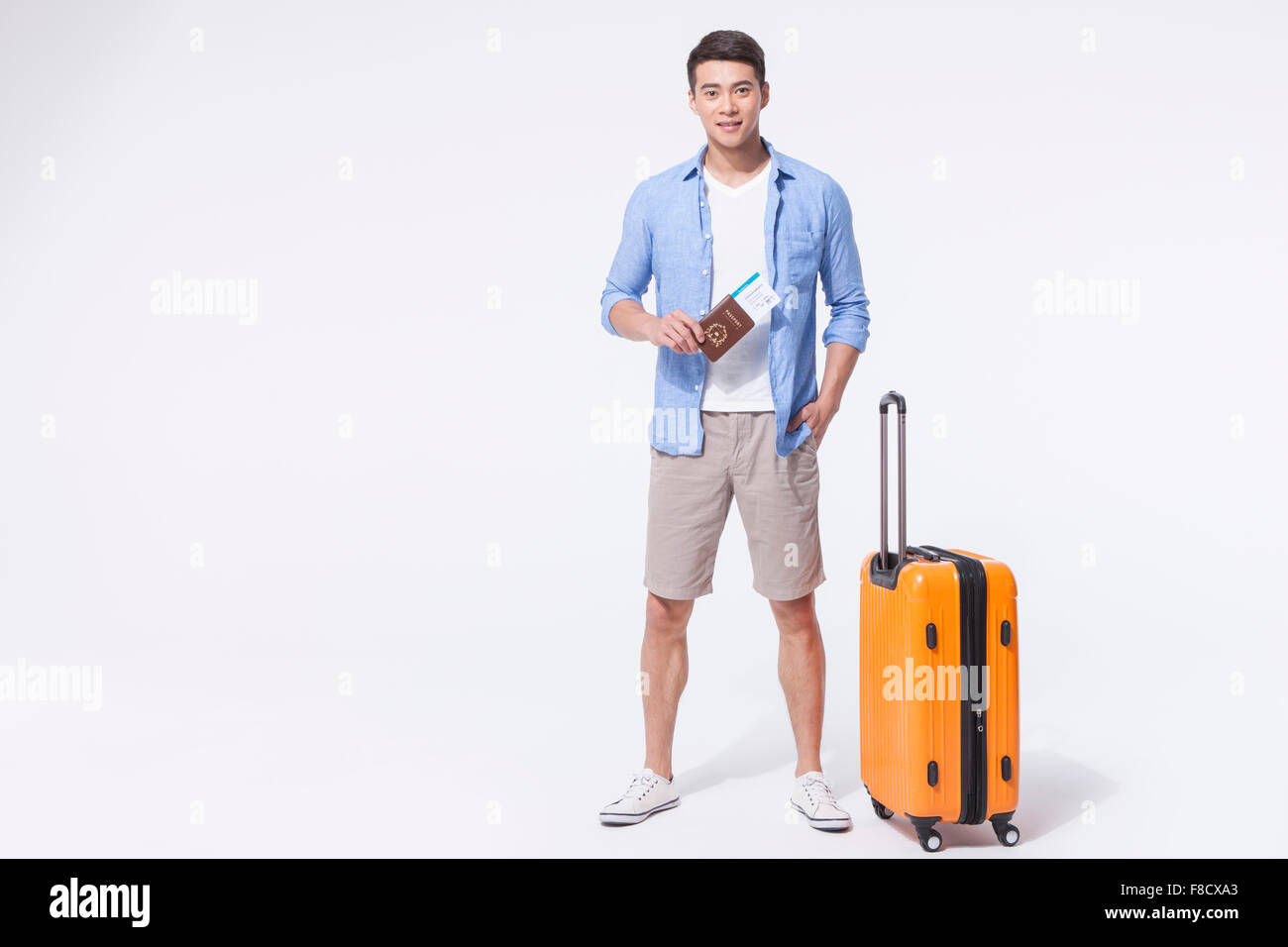 Dans l'homme tenues décontractées debout avec la valise, et tenant son passeport et billets d'avion Banque D'Images