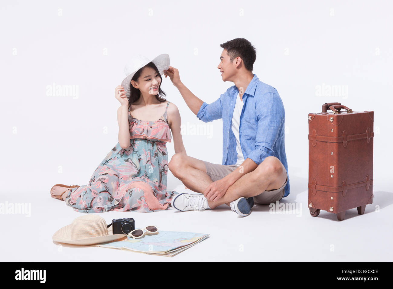 Dans l'homme tenues décontractées assis sur le plancher avec une femme en robe et un chapeau et toucher son chapeau à chaque fois à la recherche d'autres avec Banque D'Images