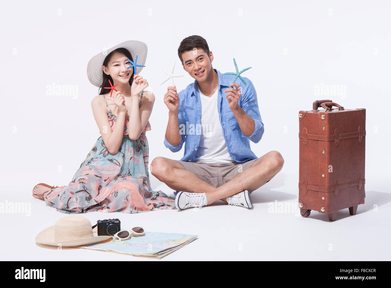 Dans l'homme tenues décontractées assis sur le plancher avec une femme en robe portefeuille et une étoile de mer avec d'autres bibelots autour Banque D'Images