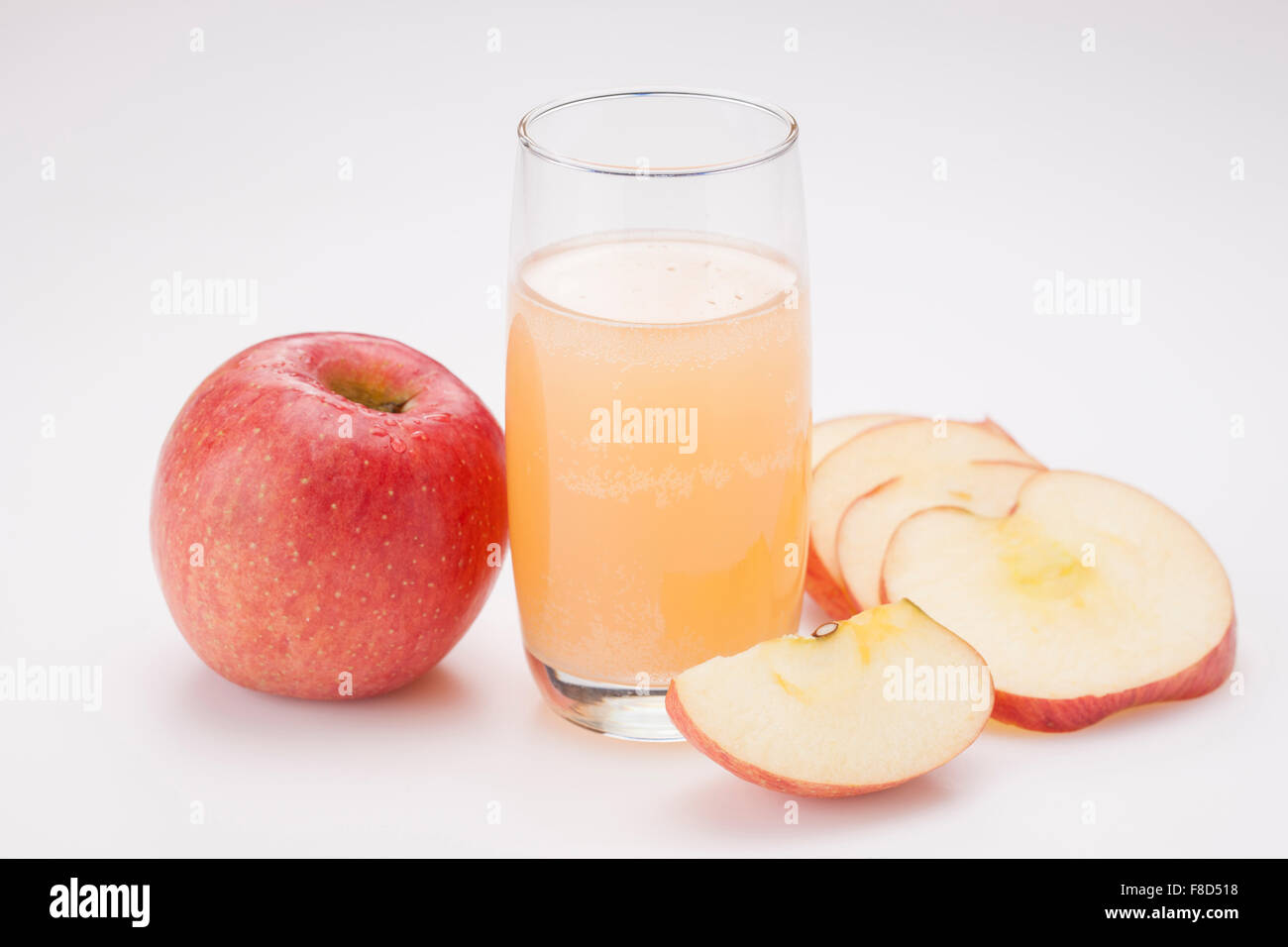 Verre de jus de pomme entre un ensemble de saveurs de pomme et de tranches de pomme Banque D'Images