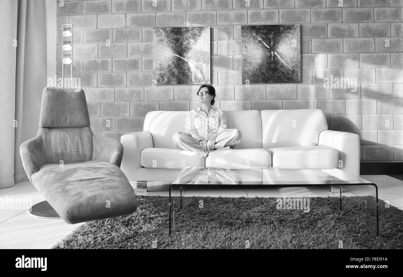 Happy young woman vous détendre à la maison sur un canapé dans la salle de séjour lumineuse et regarder la télévision Banque D'Images