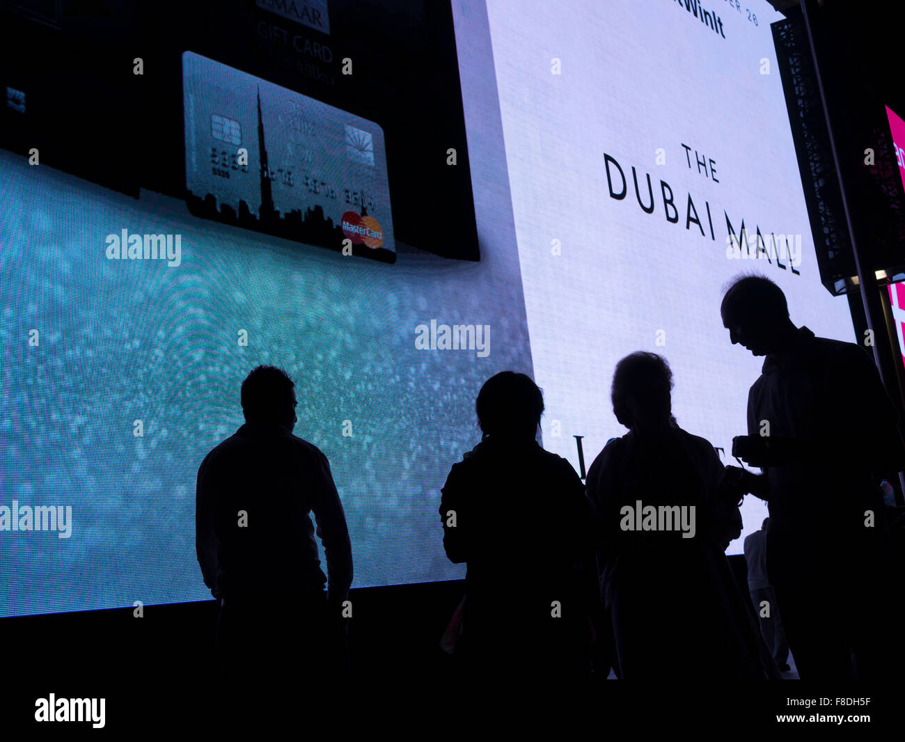 Silhouette de personnes en face de l'écran numérique géant de la publicité commerciale dans le centre commercial de Dubaï, Dubaï, Emirats Arabes Unis. Banque D'Images