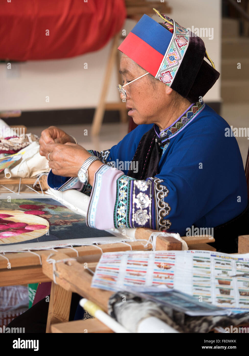 Une vieille femme ethnique Yi personnes portant des costumes traditionnels tapisserie Couture Dessins Dans Suogeyi Village, Yunnan, Chine Banque D'Images