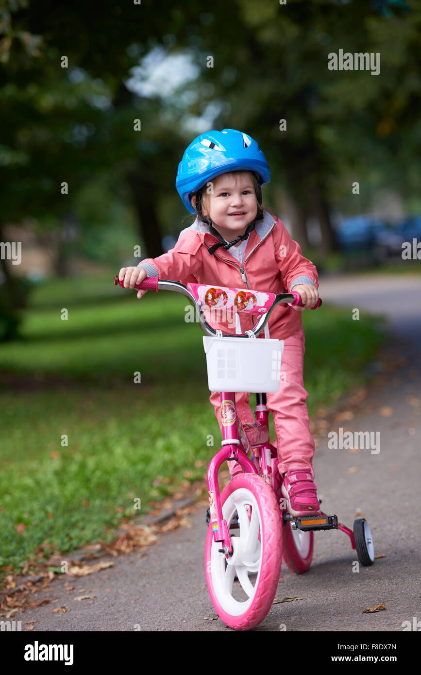 Cute smiling little girl avec Vélo et casque sur la route dans le parc Banque D'Images