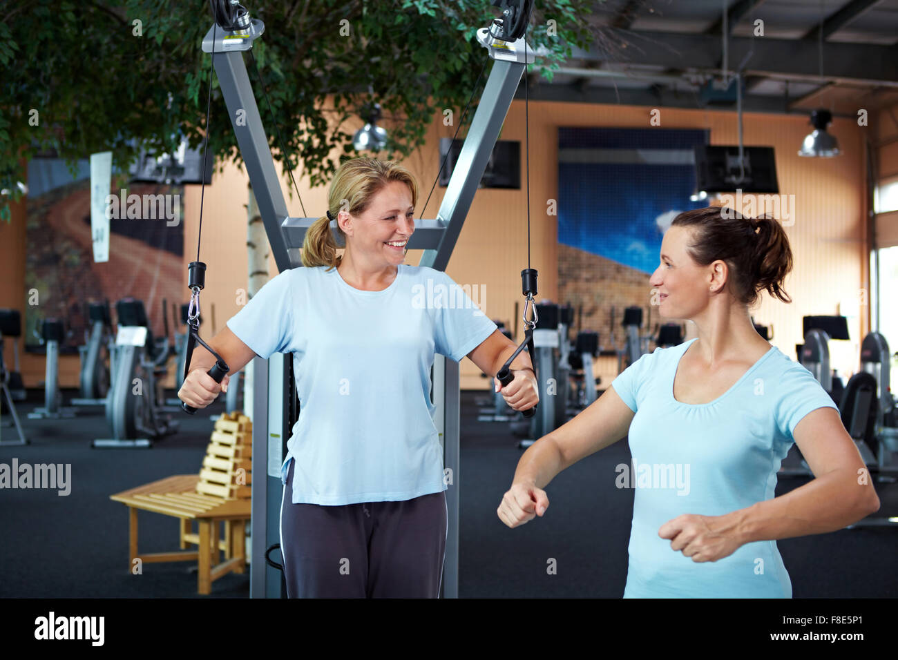 Coach fitness féminin d'aider une autre femme dans la salle de sport Banque D'Images