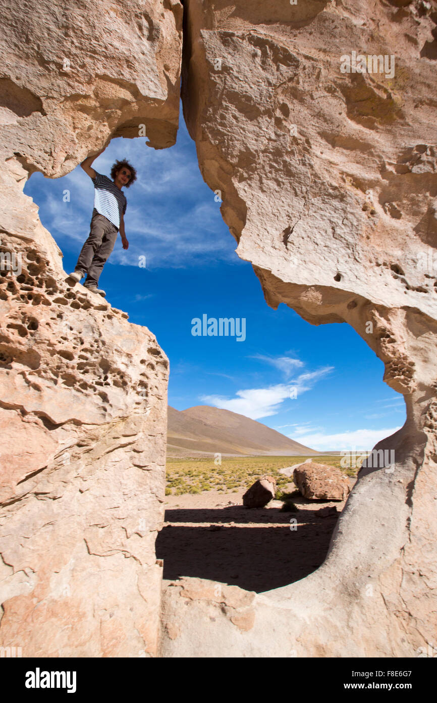 Homme debout sur une formation rocheuse géologique avec forme contre un ciel bleu clair. Bolivie 2014 Banque D'Images