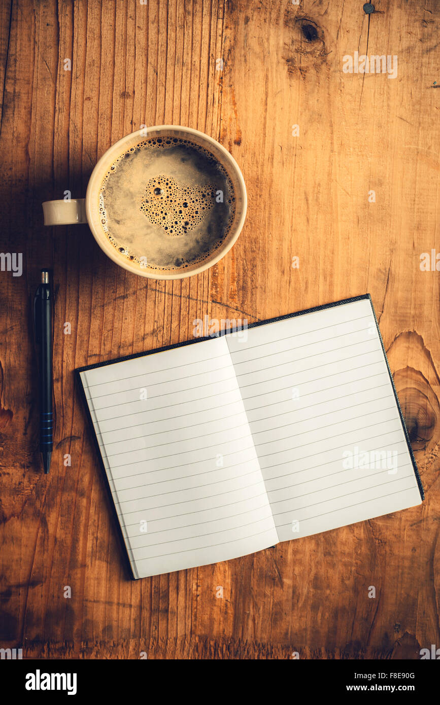 Vue de dessus de l'ordinateur portable ouvert avec des pages blanches, l'écriture crayon et tasse de café sur le vieux bureau en bois, tons rétro droit Banque D'Images